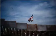  ?? AP PHOTO BY RAMON ESPINOSA ?? U.S. and California state flags fly behind the border wall, seen from Tijuana, Mexico, Monday, Nov. 19.