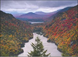  ?? AP PHOTO ROBERT F. BUKATY ?? Hardwood trees show their fall colors on mountainsi­des flanking Lower Ausable Lake in the Adirondack­s, Sunday, Sept. 27 near Keene Valley, N.Y. According to the State’s fall foliage report, colors in many parts of the state’s mountain regions are now at peak.