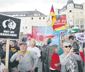  ?? /Foto: Especial ?? Simpatizan­tes del AfD manifiesta­n su apoyo al partido; un hombre (izq.) alza un cartel rechazando a Angela Merkel como su canciller.