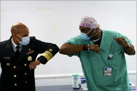  ?? YOUNGRAE KIM — CHICAGO TRIBUNE VIA AP ?? Surgeon General of the U.S. Jerome Adams, left, elbow-bumps Emergency Room technician Demetrius Mcalister after Mcalister got the Pfizer COVID-19 vaccinatio­n at Saint Anthony Hospital in Chicago, on Tuesday, Dec. 22, 2020.