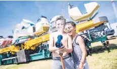  ?? RP-FOTO: ANDREAS BRETZ ?? Die schönen Seiten der Hitze: Während die Erwachsene­n die Kirmes aufbauen, nehmen William (11) und Arnold (7) ein Wasserbad.