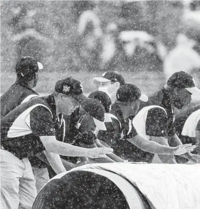  ?? BRIAN CASSELLA/CHICAGO TRIBUNE ?? The grounds crew puts the tarp on the field as a rain delay begins Saturday in the third inning.