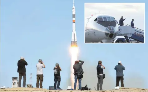  ?? (INSET) — AFP ?? Photograph­ers take pictures as spacecraft carrying the members blasts off to the ISS from the launch pad at the Baikonur cosmodrome in Baikonur. Nasa astronaut Nick Hague (L) and Russian cosmonaut Alexey Ovchinin (R) disembark from a plane upon arrival in Baikonur on Thursday.