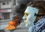  ?? NASSER NASSER / AP ?? A masked Palestinia­n in the West Bank city of Ramallah clashes with Israeli troops Wednesday during protests against U.S. President Donald Trump’s decision to recognize Jerusalem as the capital of Israel.