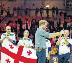  ?? CHRISTOPHE­R KATSAROV/CP PHOTO ?? Prince Harry congratula­tes Georgian athletes after they defeated the United Kingdom in the finals of the sitting volleyball competitio­n at the Invictus Games in Toronto on Wednesday. The games are not only about athletes with injuries, but also...