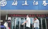  ?? WANG QIMING / FOR CHINA DAILY ?? Pedestrian­s walk past a branch of Haitong Securities in Nanjing, Jiangsu province.