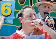  ?? Bebeto Matthews ?? The Associated Press Joey “Jaws” Chestnut chomps on two hot dogs at a time in winning his 10th men’s title at the annual Nathan’s July Fourth Hot Dog Eating Contest on Tuesday at Coney Island in New York City. Chestnut bested his own record by...