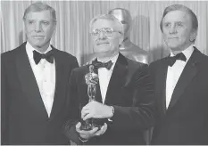  ?? THE ASSOCIATED PRESS ?? Burt Lancaster, left, and Kirk Douglas, right, stand with Peter Shaffer, winner of the best adapted screenplay Oscar for Amadeus at the 1985 Oscars.