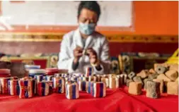  ??  ?? 藏香厂的彩绘师傅，正在为藏香底座涂颜料。