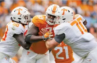  ?? STAFF PHOTO BY C.B. SCHMELTER ?? Orange Team defensive lineman Emmit Gooden (93) fights against blocks from White Team offensive linemen Jahmir Johnson (58) and Ryan Johnson (70) during the Orange and White spring football game in April.