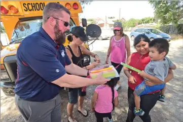  ?? Dan Watson/The Signal ?? Jesus Montoya, 2, right, gets a frozen treat from Castaic Union School District Superinten­dent Steve Doyle, left, and members of the district during the Castaic Welcome Wagon tour in Val Verde on Tuesday.