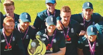 ?? AFP ?? England’s captain Eoin Morgan (centre) holds the series trophy along with teammates after the fifth ODI match against Australia at Old Trafford ground in Manchester.
