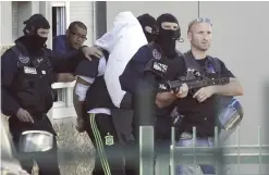  ??  ?? LYON: In this June 28, 2015 file photo, the suspect in the beheading of a businessma­n, Yassine Salhi, a towel over his head to mask his face, is led by police officers as they leave his home in Saint-Priest. — AP