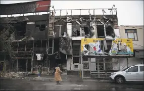  ?? Masoume Aliakbar / Associated Press ?? In this photo taken Monday and released by Iranian Students’ News Agency, ISNA, people walk past buildings which burned during protests that followed the authoritie­s’ decision to raise gasoline prices, in the city of Karaj, west of the capital Tehran, Iran. An article published Tuesday in the Keyhan hardline newspaper in Iran is suggesting that those who led violent protests will be executed by hanging as the unrest continues.