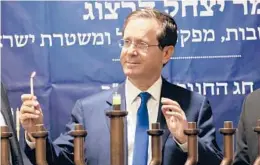  ?? OREN ZIV/AP ?? Israeli President Isaac Herzog lights a candle to celebrate the opening night of the eight-day Jewish holiday of Hanukkah on Sunday in the West Bank city of Hebron.