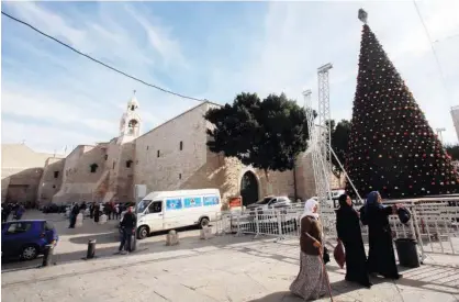  ?? Reuters ?? Palestinia­n women walk past a Christmas tree outside the Church of the Nativity in Bethlehem in the occupied West Bank on Wednesday.