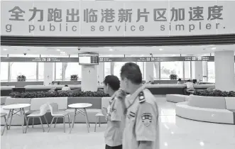  ??  ?? Officers walk in a government service center in Lingang, a newly added area in the Shanghai free trade zone. — Xinhua