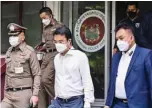  ?? ?? BANGKOK: Photo shows Prinn Panitchpak­di (C), a former deputy of Thailand’s Democrat Party, as he leaves a police station in Bangkok on his way to court to ask for bail. —AFP