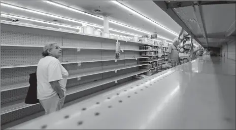  ?? DAVID J. PHILLIP/AP PHOTO ?? Shoppers pass empty shelves along the bottled water aisle in a Houston grocery store as Hurricane Harvey intensifie­s in the Gulf of Mexico on Thursday. Harvey is forecast to be a major hurricane when it makes landfall along the middle Texas coastline.