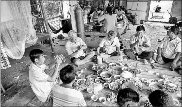  ??  ?? Shrimp farmers listen to a friend sing karaoke during a meal celebratin­g the return of a friend from a successful trip to China.