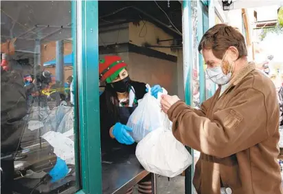  ?? ANA RAMIREZ U-T ?? Volunteer director Laura Kojima hands a meal to William Nelson courtesy of Father Joe’s Villages in San Diego on Friday.