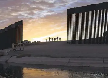  ?? EUGENE GARCIA AP FILE ?? A pair of migrant families from Brazil seeking asylum walk through a gap in the border wall to reach the United States after crossing from Mexico to Yuma, Ariz., on June 10, 2021.