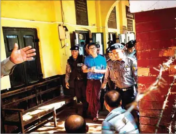  ?? YE AUNG THU/AFP ?? Reuters journalist Wa Lone (centre) is escorted by police out of court in Yangon yesterday.