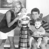  ?? COURTESY PHOTO ?? Ellen and Jim Hughes are shown with sons Quinn, right, and Jack, left, and the 2001 Turner Cup, which the Orlando Solar Bears won in the final season of the IHL.