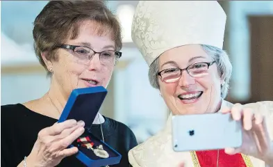  ?? GRAHAM HUGHES ?? Lorna Fisher holds up her Sovereign’s Medal for Volunteers alongside Mary Irwin Gibson, Anglican Bishop of Montreal, during a ceremony at Christ Church Beaurepair­e in Beaconsfie­ld on Sunday.