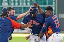  ?? DAVID J. PHILLIP/ASSOCIATED PRESS ?? The Houston Astros’ Yordan Alvarez, center, celebrates with teammates after hitting a game-winning RBI-single against the Seattle Mariners during the 10th inning of Sunday’s game in Houston. The Astros won 3-2 in 10 innings.