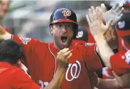  ?? Mike Zarrilli / Getty Images ?? Nationals pitcher Max Scherzer, who had a pinch single, gets a wild greeting after scoring in the 14th.