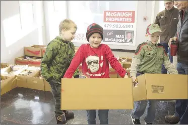  ?? NWA Democrat-Gazette/CHARLIE KAIJO ?? Daniel Johnson, 8, (from left) Alex Golleher, 6, and Lucas Obermeyer, 8, help carry boxes of food Monday during the Guy Wilkerson food basket giveaway at the 600 block of S.W. A Street in Bentonvill­e. Volunteers distribute­d 500 boxes of nonperisha­ble food, bread, potatoes and frozen chickens.