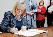  ??  ?? Gov. Mary Fallin signs commutatio­ns on Wednesday for 21 Oklahoma inmates who were serving sentences of 10 years or longer for drug possession and other crimes that now carry lesser punishment­s.