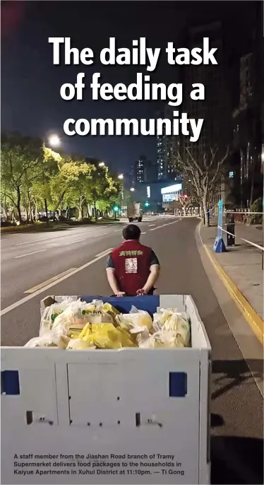  ?? — Ti Gong ?? A staff member from the Jiashan Road branch of Tramy Supermarke­t delivers food packages to the households in Kaiyue Apartments in Xuhui District at 11:10pm.
