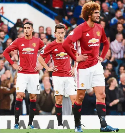  ?? Dejected Devils: ?? Manchester United’s (from left) Chris Smalling, Ander Herrera and Marouane Fellaini react after Chelsea scored the second goal in the English Premier League match at Stamford Bridge on Sunday. Chelsea won 4-0. — EPA