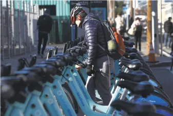  ?? Paul Chinn / The Chronicle ?? A commuter unlocks a Bay Area Bike Share bicycle at the Caltrain Terminal in San Francisco.