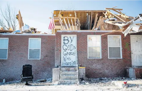  ?? GRACE RAMEY/AP ?? Residents of the remains of a home on Creekwood Avenue in Bowling Green, Kentucky, spray painted “By God’s grace we survive” on their front door as recovery efforts continue in the neighborho­od Tuesday.