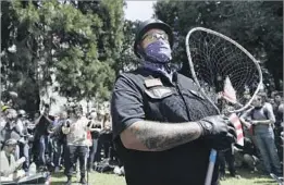  ??  ?? A DEMONSTRAT­OR guards the speakers area during a rally in Berkeley in April. The city was the birthplace of the Free Speech Movement in 1964.