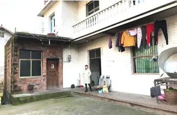  ??  ?? The wife of silicosis patient Wang Zhaohong stands in front of their house in Sangzhi county, Hunan province, China. — Reuters photo