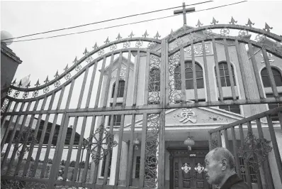  ?? Associated Press ?? ■ ABOVE: A man stands June 2 outside the gated entrance near the Chinese character for "Love" above the door of a church in central China's Henan province. ■ BELOW: Xu Shijuan talks about her faith June 3 at her home in Zhengzhou in central China’s...