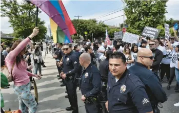  ?? RICHARD VOGEL/AP ?? Protesters shout slogans and carry signs as Los Angeles police officers separate them from counterpro­testers Friday at Saticoy Elementary School in the North Hollywood section of Los Angeles. The elementary school has become a flashpoint for Pride Month events and activities across California with people protesting a planned Pride Month assembly.