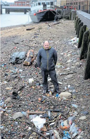  ?? Pictures: STEVE BELL ?? Express reporter David Pilditch inspects rubbish strewn on the Thames riverbank