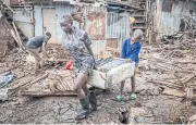  ?? AFP ?? A girl and a boy salvage a piece of furniture from their house, which was destroyed by floods following torrential rains at the Mathare informal settlement in Nairobi.