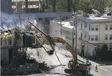  ?? Leah Millis / The Chronicle ?? Workers survey damage next to a downed constructi­on crane, top, as the Oakland Fire Department removes rubble from the blaze at a seven-story building under constructi­on, above.