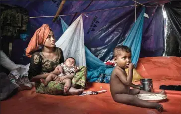  ?? ADAM DEAN/THE NEW YORK TIMES ?? Recently arrived Rohingya refugees eat in a makeshift shelter near Kutupalong, Bangladesh, on September 9.