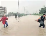  ?? ANI ?? Students cross a waterlogge­d street in front of Bhagwan Mahavir University following incessant rain in Surat.