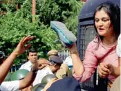  ??  ?? A Congress activist shows her shoe to police personnel after being detained in front of Writers Building, while protesting against chit fund scam in Kolkata on Monday.