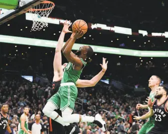  ?? Kathryn Riley / Getty Images ?? Kemba Walker of the Celtics drives to the basket against Marc Gasol of the Raptors in the second half in Boston. Walker scored 11 of his 22 points in the fourth quarter to lead the win.