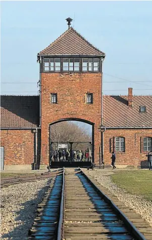  ?? | PHOTO : F. DUBRAY, O.-F. ?? Devant l’entrée du camp de concentrat­ion d’Auschwitz-Birkenau.