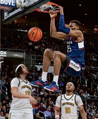  ?? MARK STOCKWELL/ASSPCIATED PRESS ?? UConn’s Samson Johnson (8 points) finishes a slam after topping the Providence defense of Josh Oduro (left) and Rich Barron in the road win.